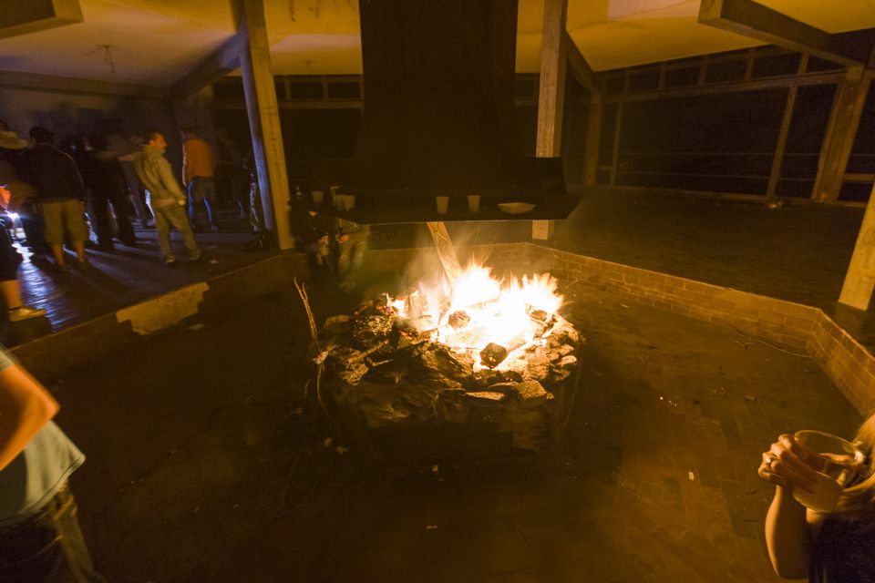 Bonfire burning in a concrete pit as guests gather in the dark