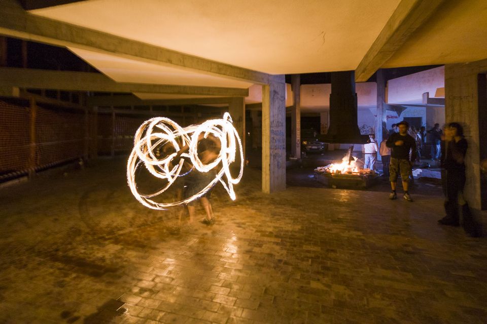 Fire spinner’s glowing trails under a concrete canopy