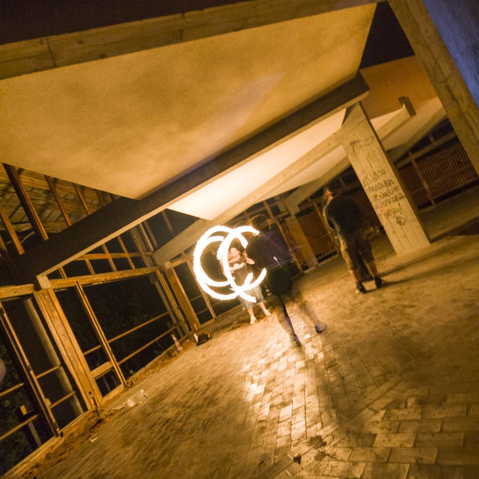 Fire spinner tracing circles beneath slanted concrete beams