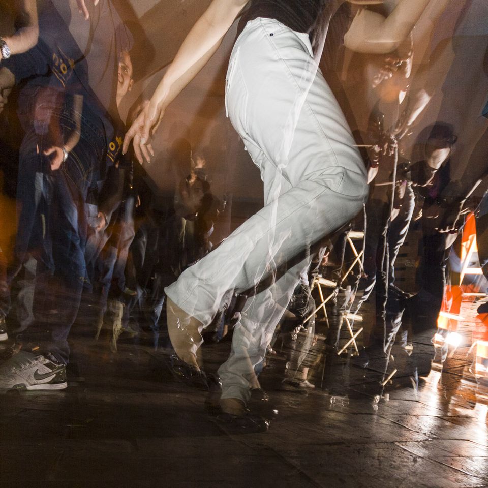 Dancer in white trousers caught in a blur of motion