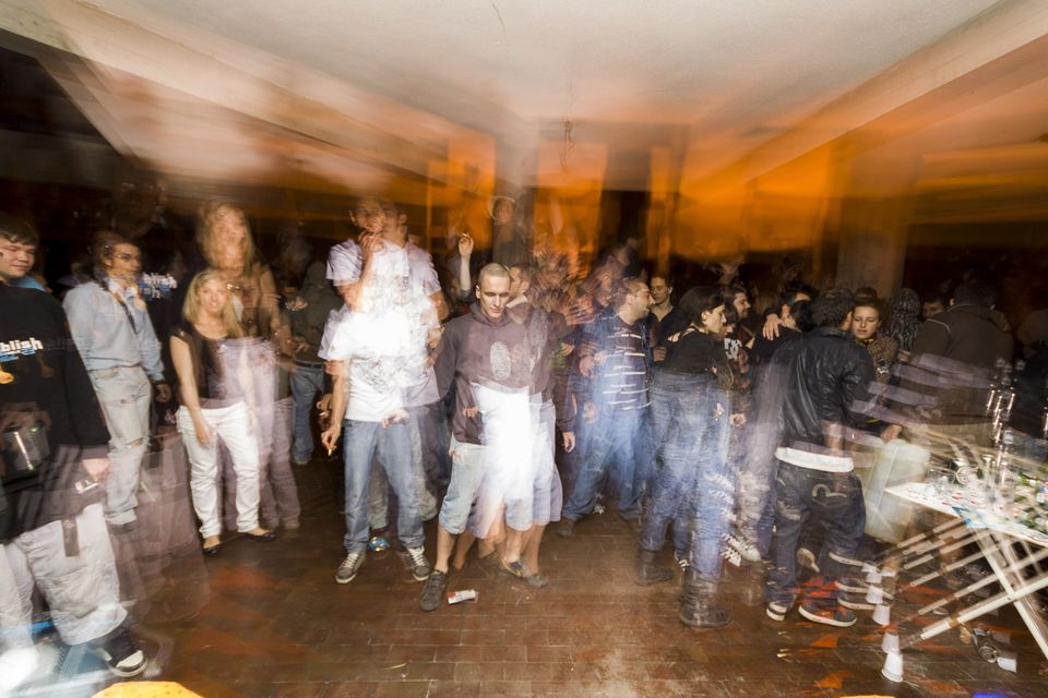 Blurred dancers under orange light in a crowded hall