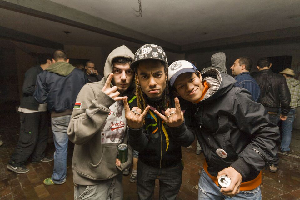 Three friends flashing hand signs at the camera with drinks