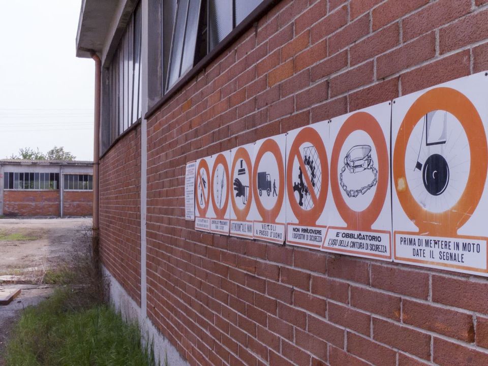 Row of orange safety signs on a brick factory wall