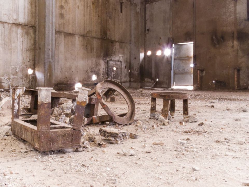 Rusted frames and a stool in a bare concrete hall