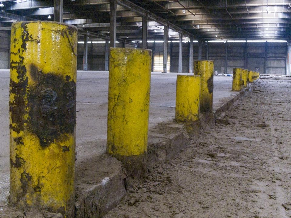 Yellow bollards lining the edge of a vast empty factory hall