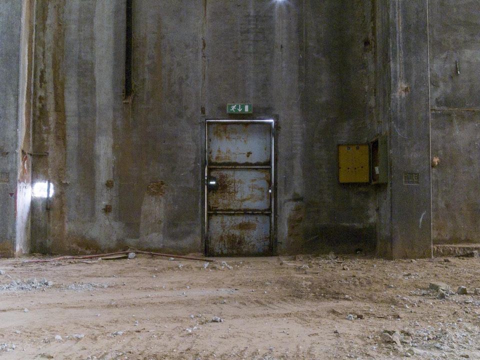 Rusted metal door in a tall stained concrete wall