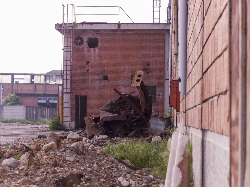 Rusting scrap in front of a brick tower with a ladder
