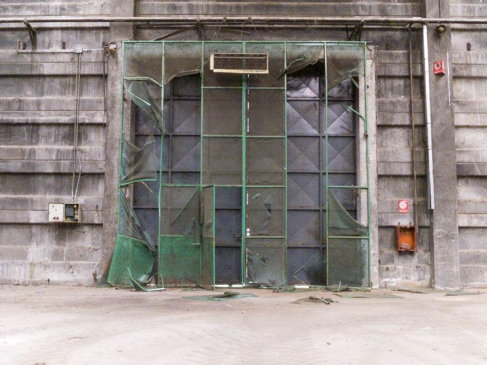 Large industrial door behind torn green wire mesh