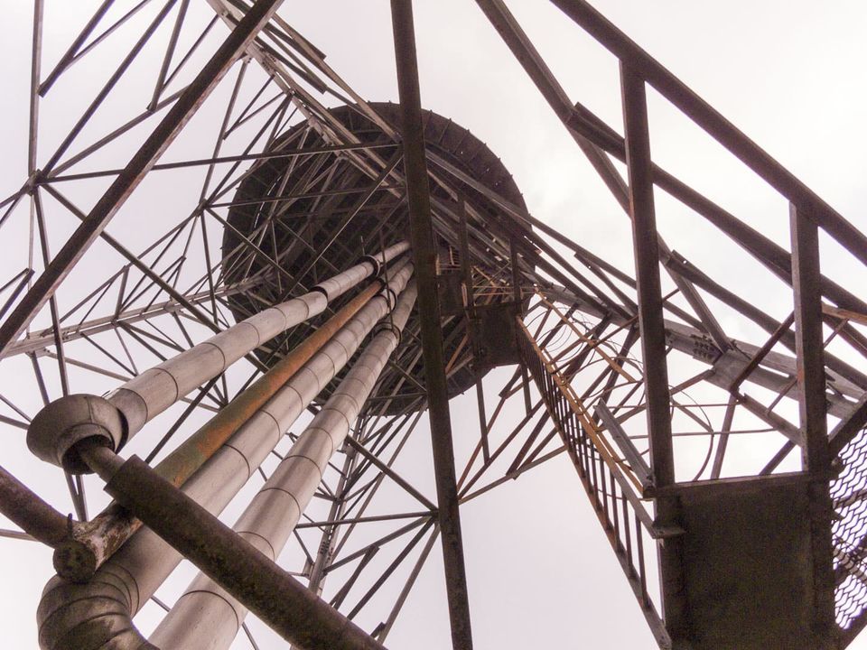 Water tower tank and pipes seen from below through steel lattice