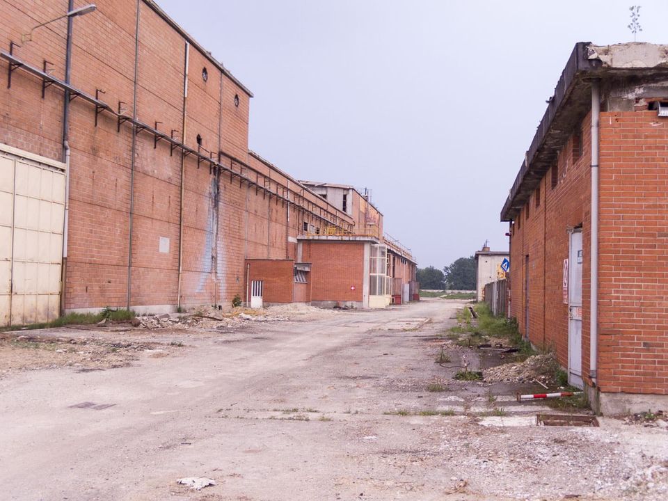 Dirt lane between tall brick factory buildings