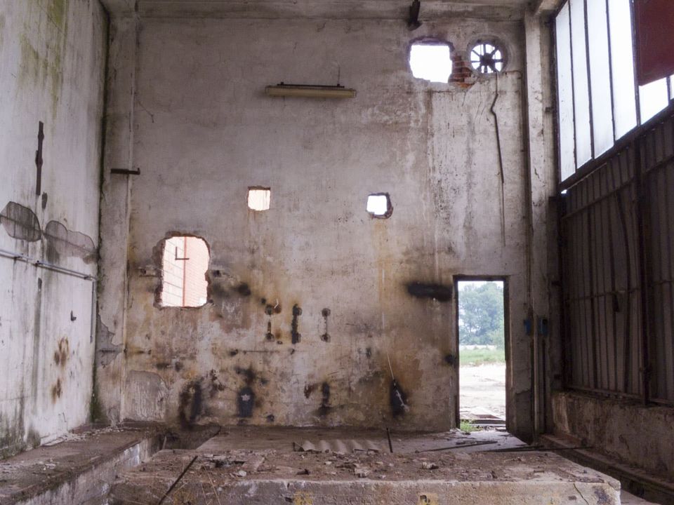 Hall wall with small window holes and an open doorway to daylight