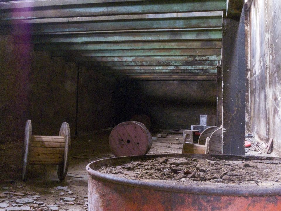 Wooden cable reels and a rusty drum in a dark low corridor