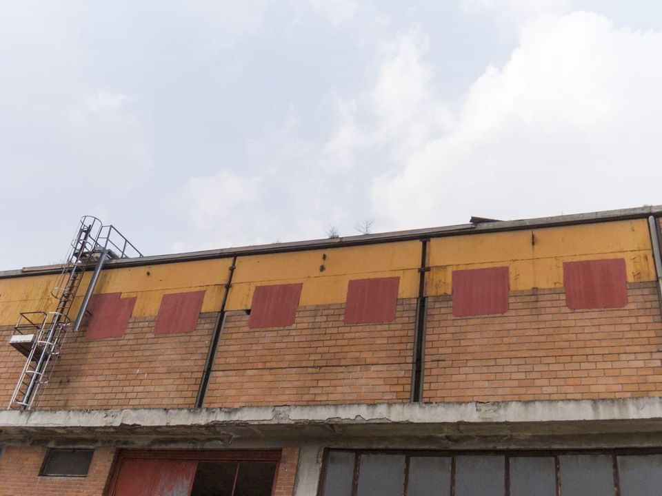 Brick wall with yellow panels, red patches and a roof ladder