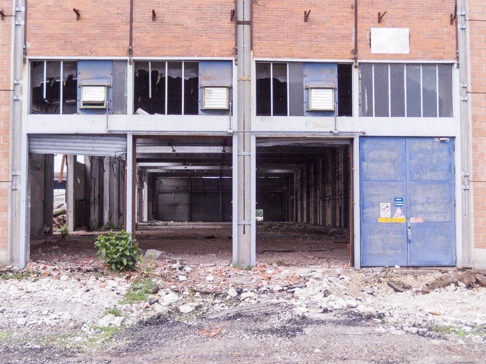 Brick building with open ground-floor bays and a blue metal door