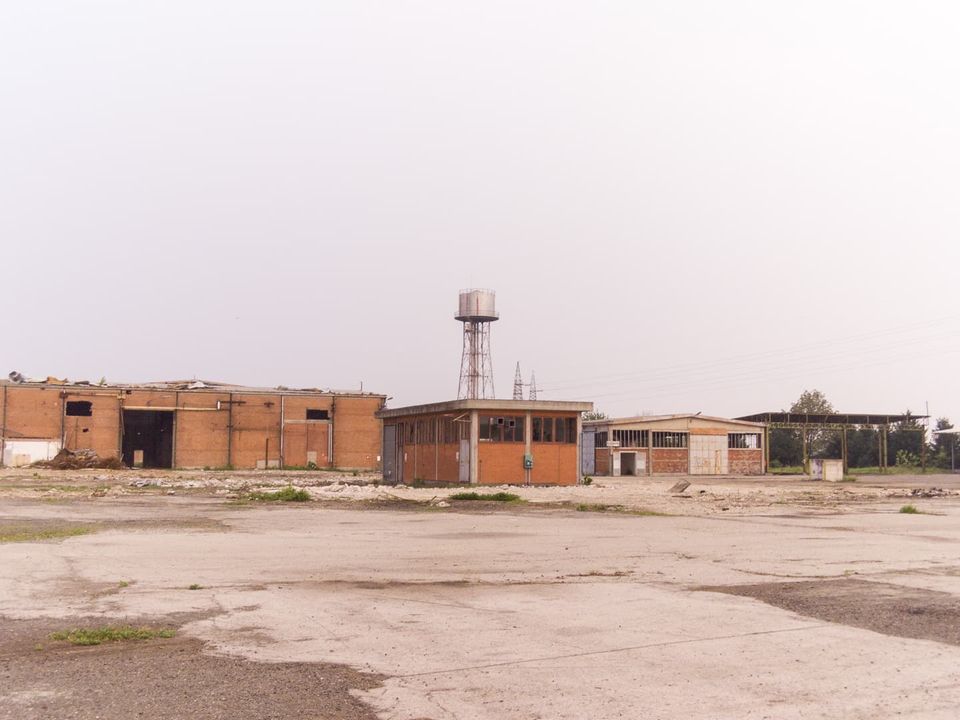 Open yard with brick sheds and a water tower in the haze