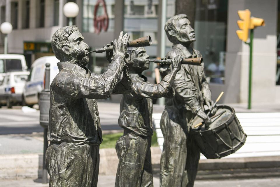 Bronze figures playing flutes and a drum on a street corner