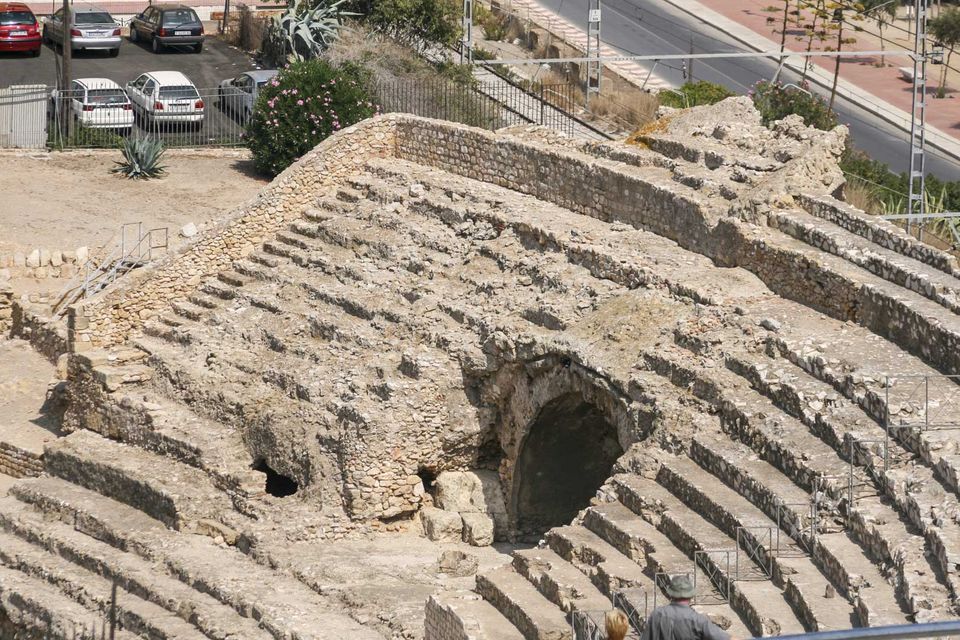 Weathered stone tiers of the amphitheatre above a car park