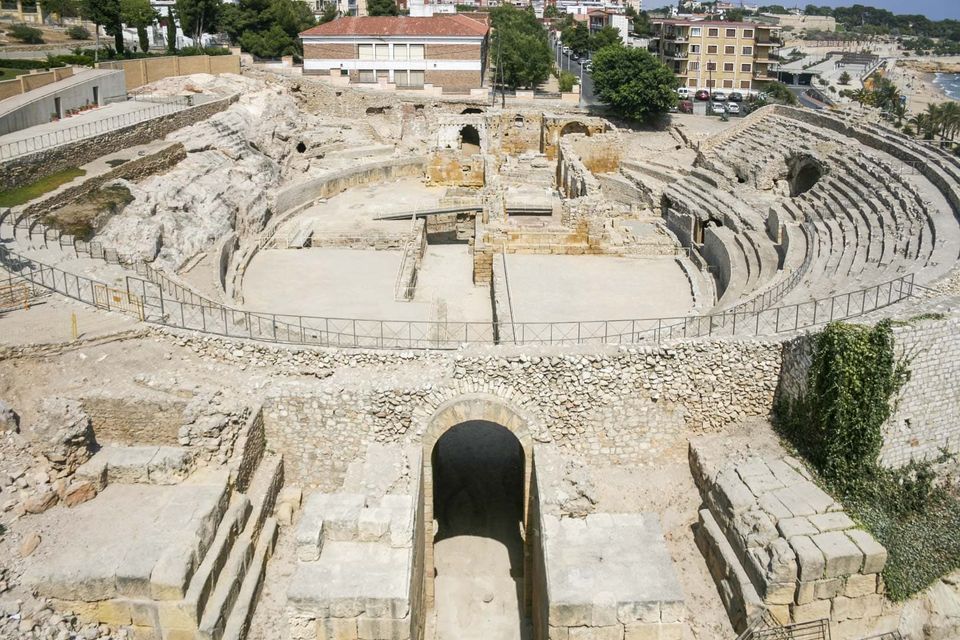 Ruined seaside amphitheatre with curved tiers and an arched entrance