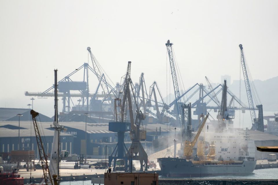 Harbour cranes and a cargo ship in morning haze