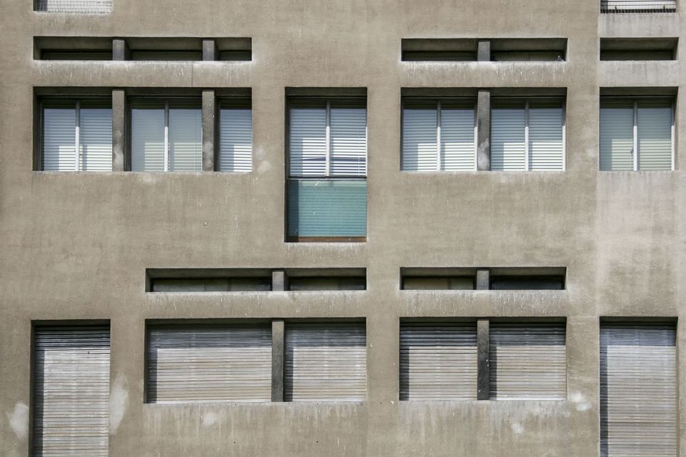 Grey concrete facade with rows of shuttered windows