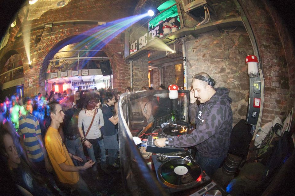 DJ at the turntables with a crowd dancing under blue stage light