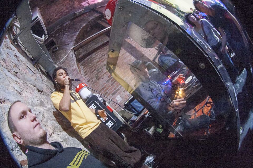 MC with a megaphone beside the booth in a stone-walled corner
