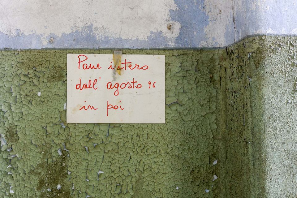 Handwritten note about bread pinned on a cracked green wall