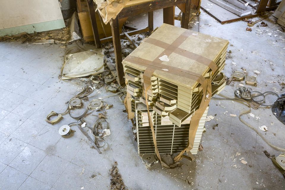Stack of old reels and tapes on a debris-strewn floor