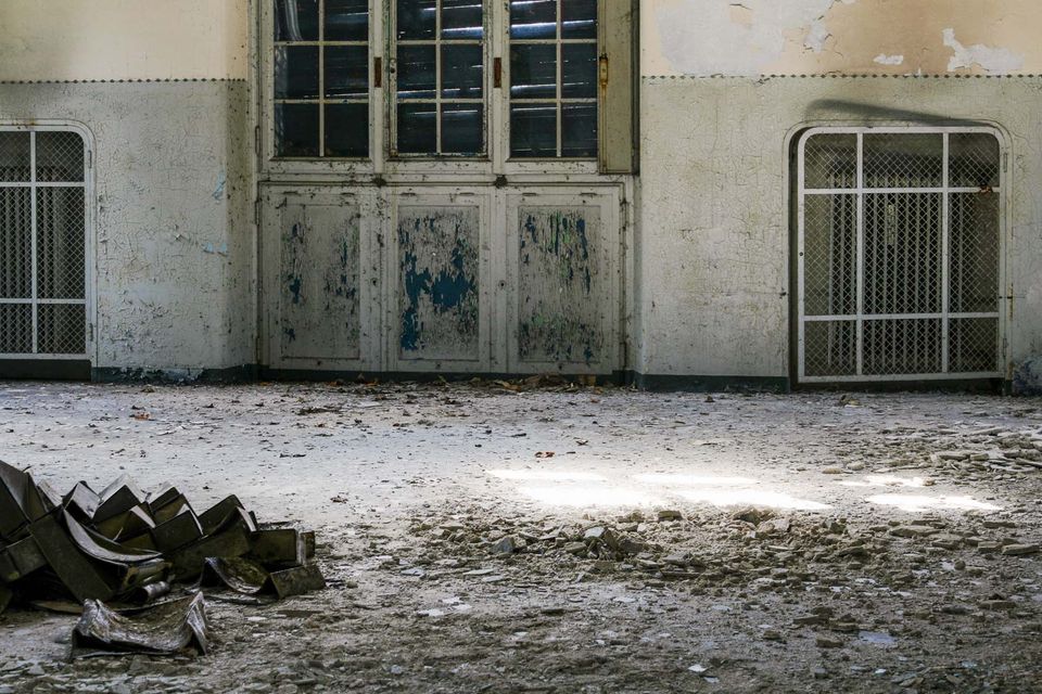 Empty hospital hall with barred doors and light on a dusty floor