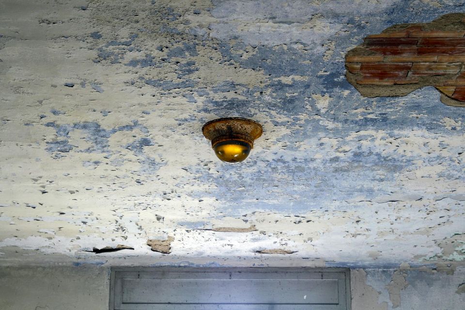 Ceiling lamp on blue peeling plaster with exposed brick