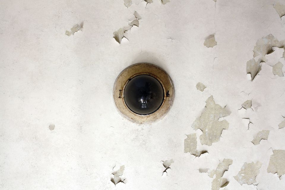 Round ceiling light on a white ceiling with flaking paint