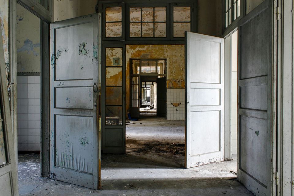 Open double doors leading through a series of derelict rooms