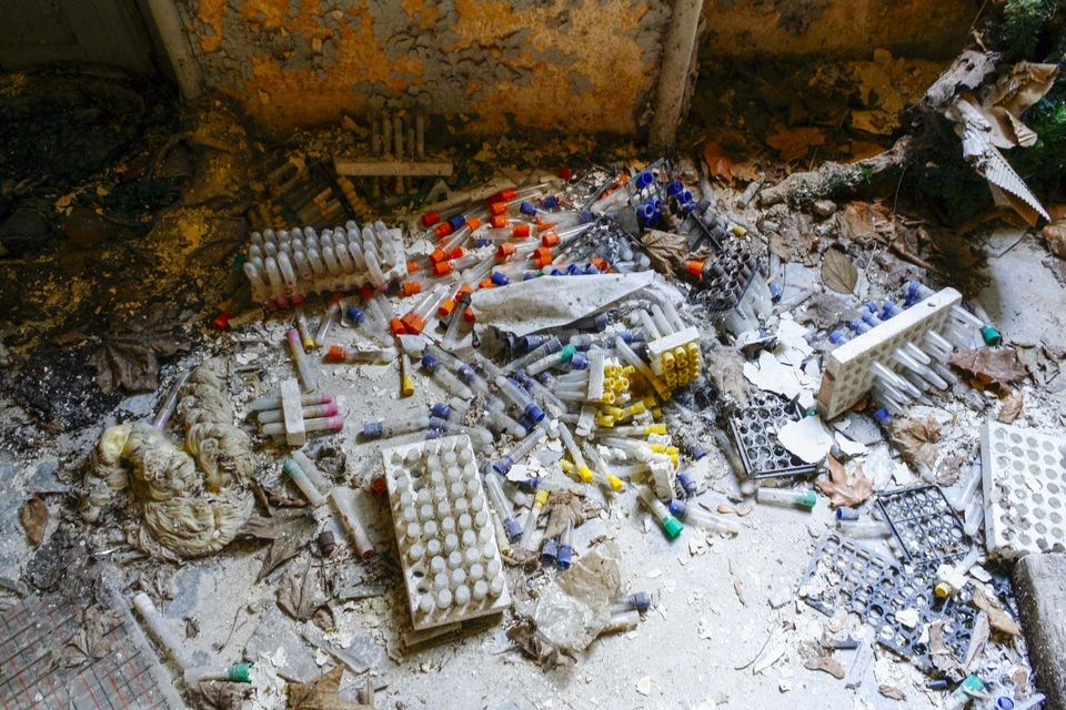 Scattered test tubes, vials and trays on a filthy floor