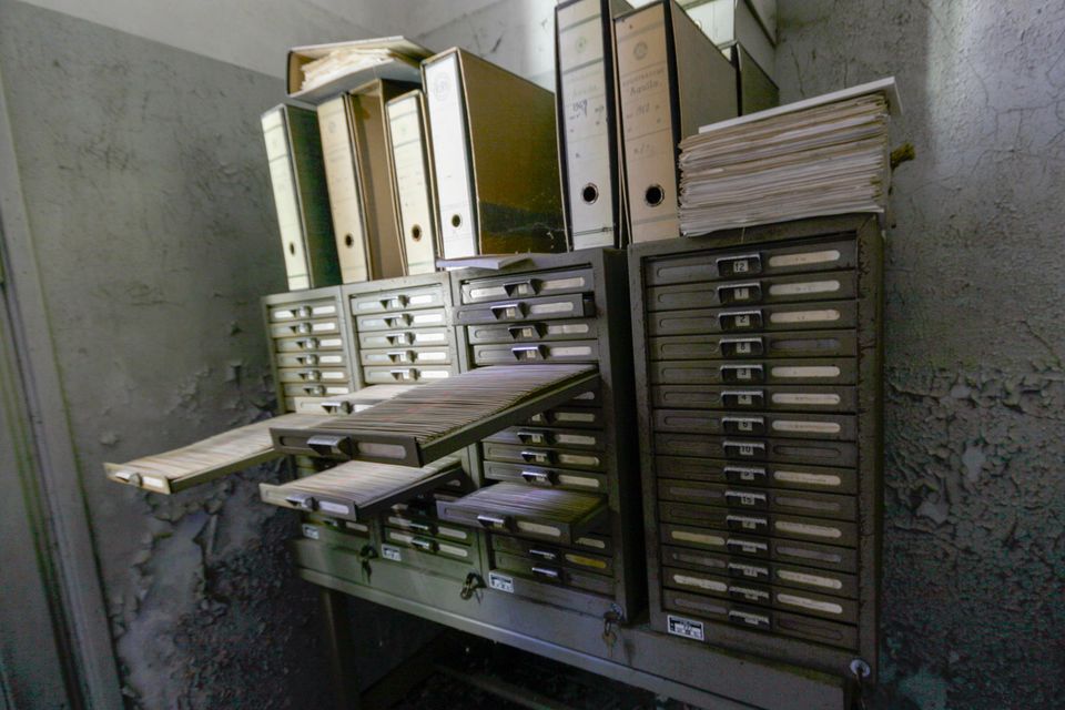 Metal filing cabinets with drawers pulled out under stacked folders