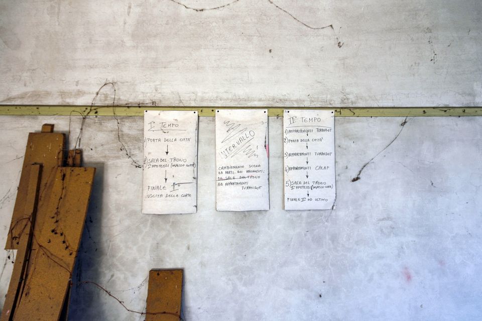 Handwritten sheets taped to a wall above stacked wooden boards