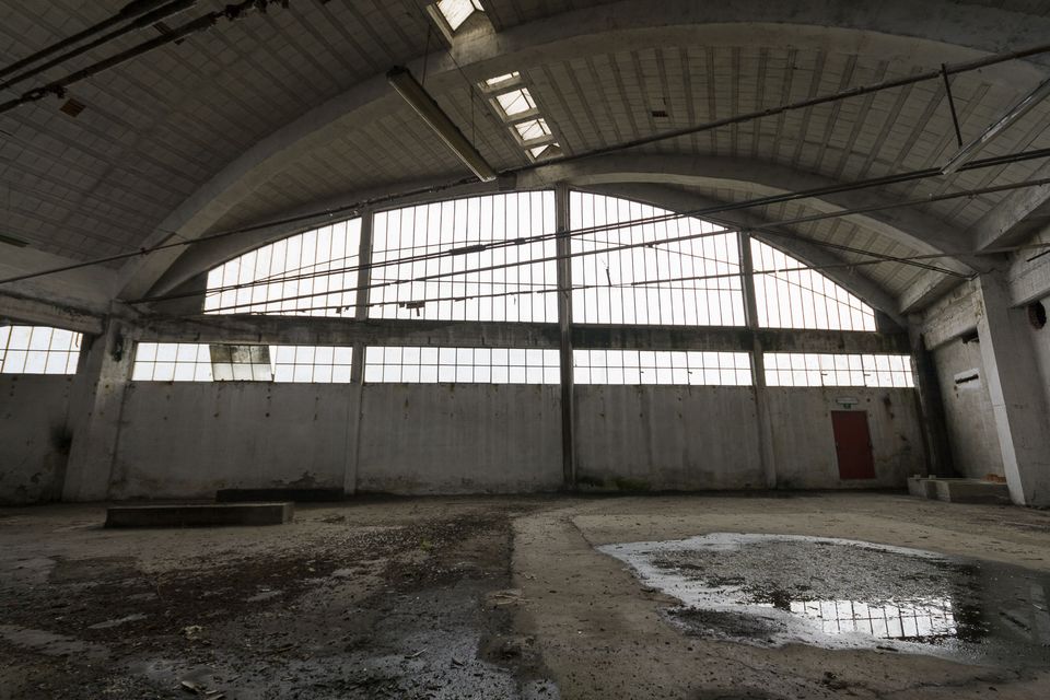 Vaulted factory hall with tall windows and a puddle on the floor
