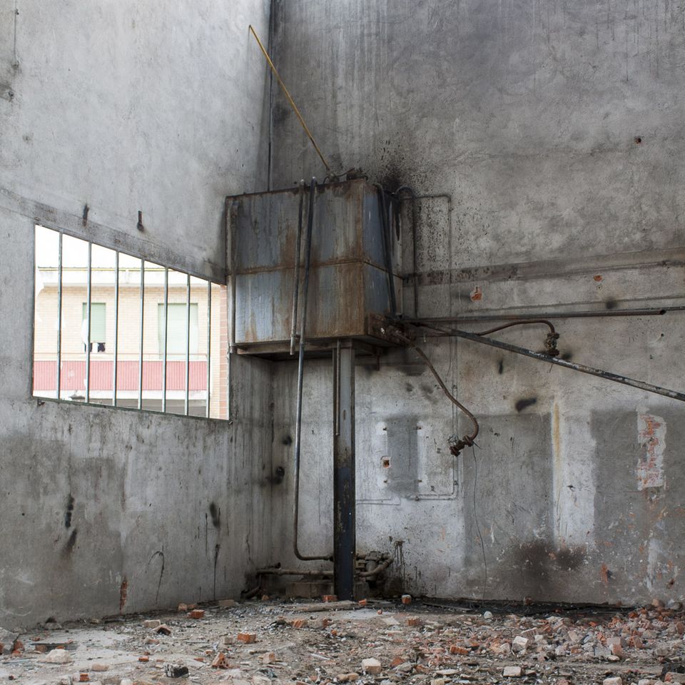 Rusty metal tank mounted in a corner of a bare room