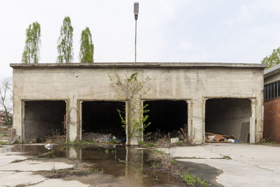 Row of open concrete garage bays beside a puddle