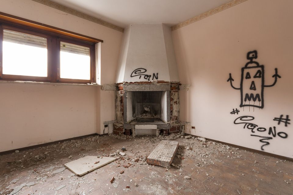 Room with a corner fireplace and graffiti on the wall