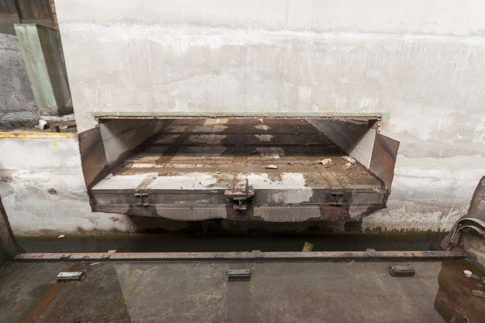 Steel loading hatch in a concrete wall above a rail