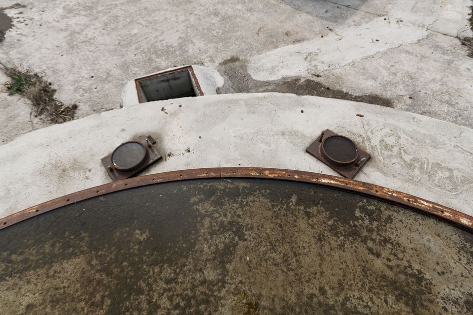 Round tank rim with two rusty lids and a drain