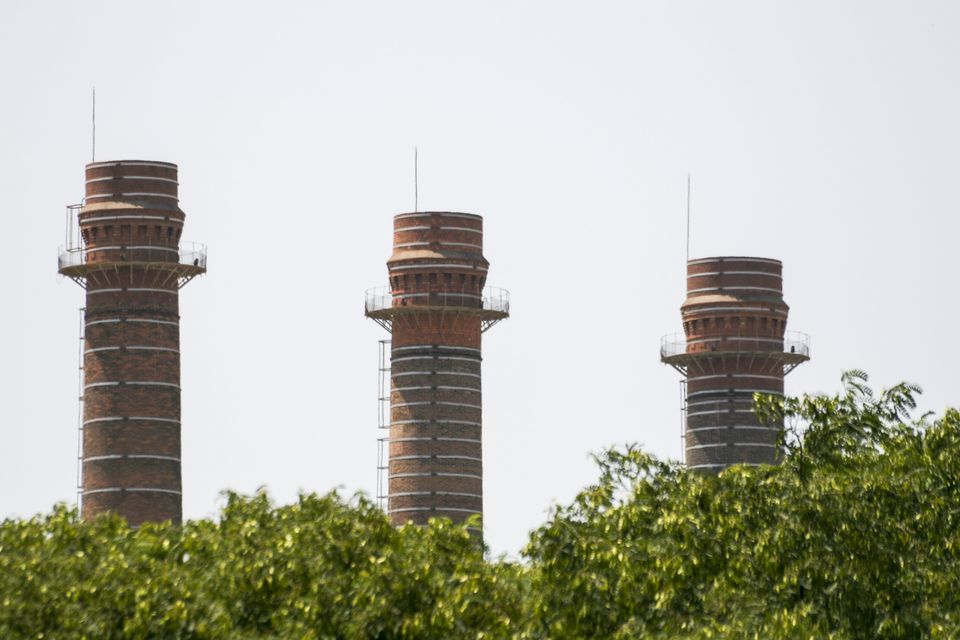 Three brick chimneys rising above green treetops