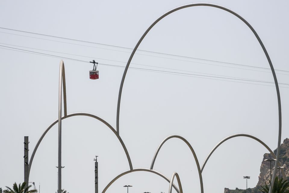 Curving steel arches with a red cable car behind
