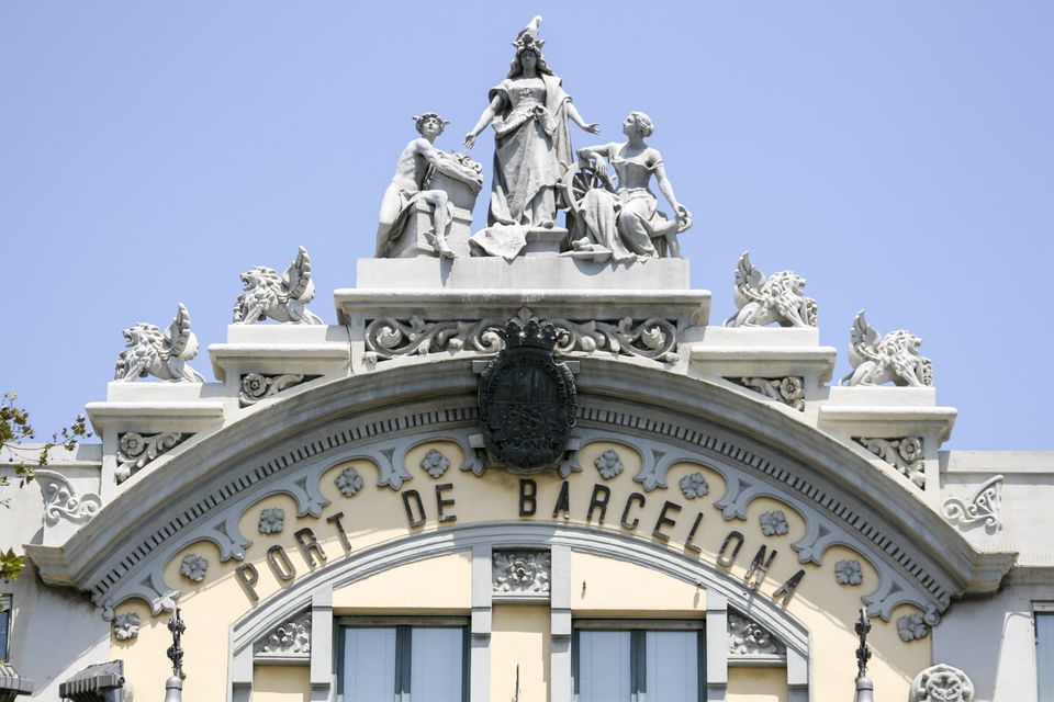 Statues crowning an arched cream facade inscribed Barcelona