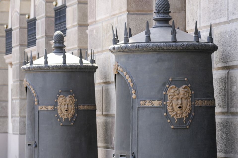 Two grey kiosks with spiked roofs and gilded face medallions