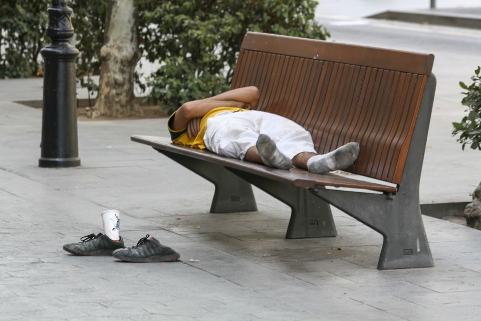 Man asleep on a wooden bench with his shoes on the ground