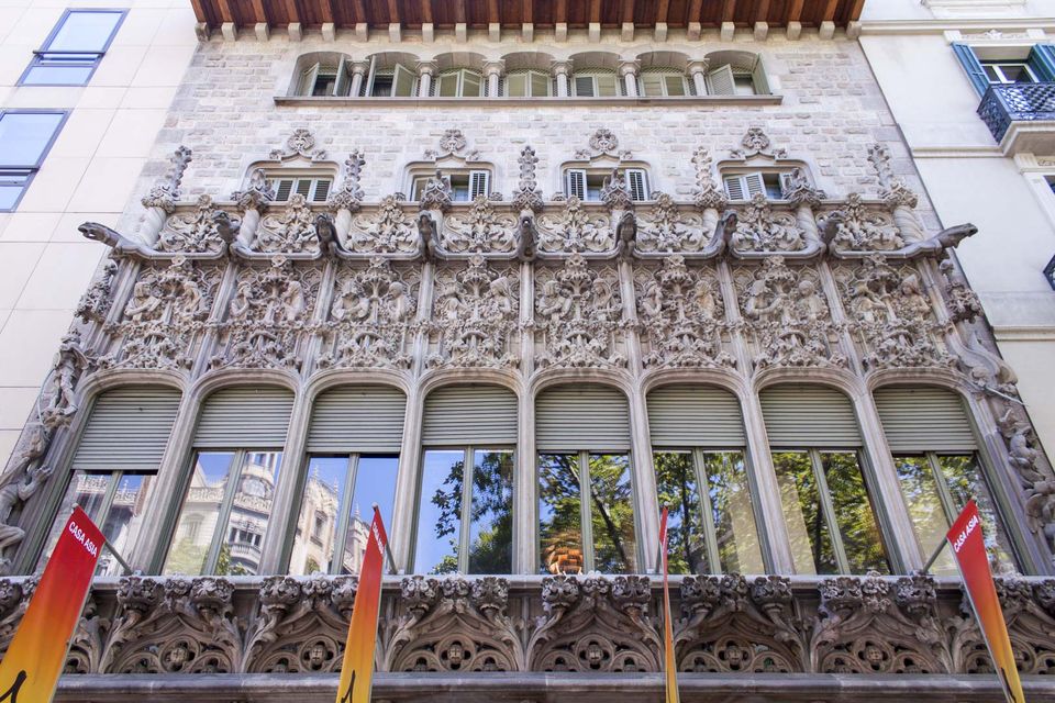 Richly carved stone facade with arched windows and red banners