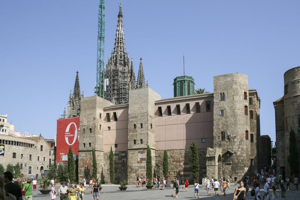 Gothic cathedral spire above stone buildings and a busy square