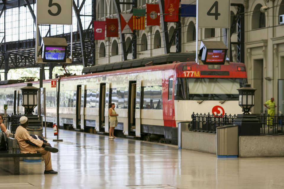 Red commuter train at a platform under an iron roof