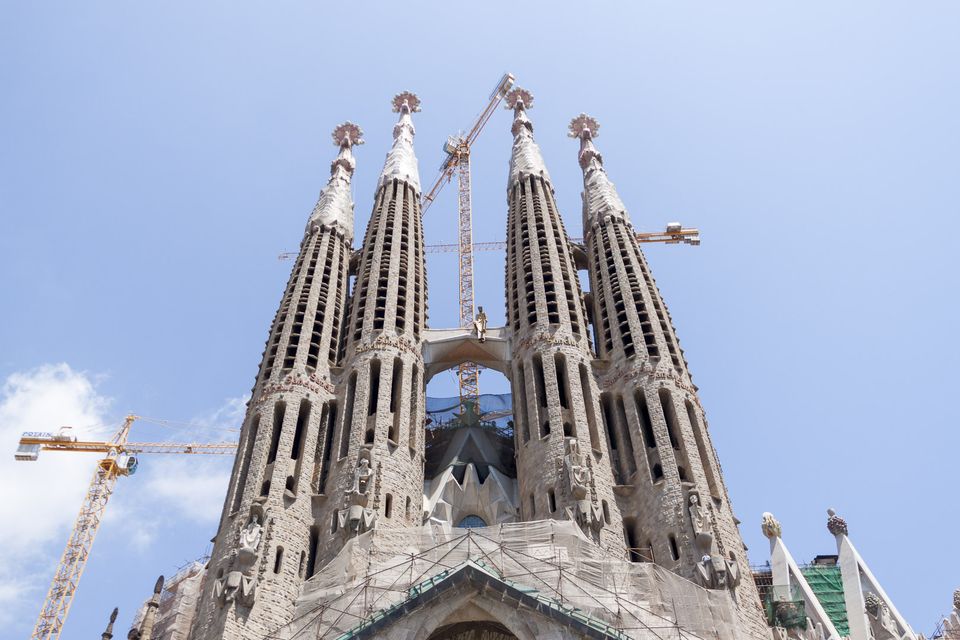 Sagrada Família spires with cranes against blue sky